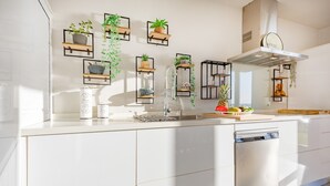A modern kitchen with white cabinetry, a dishwasher, and various plants on shelves. - Vacation Home "Mimar Urban Altea Sol" with Sea View, Private Terrace & Wi-Fi (Altea)