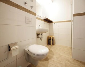 Et moderne badeværelse med toilet, vask og en lille skammel.