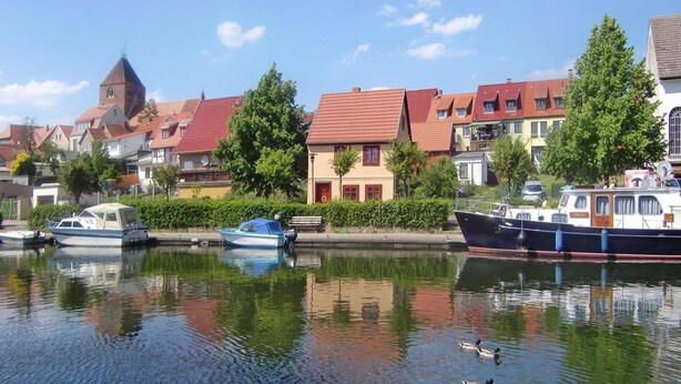 A calm waterway with boats, a duck, and buildings along the shore. - Appartement Hafenflair am Plauer See (Plau am See)