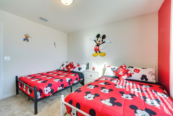 A room with two beds, each with a Mickey Mouse themed bedspread.