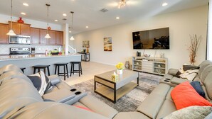 Ein modernes Wohnzimmer mit Sofa, Couchtisch und einer Küche im Hintergrund.