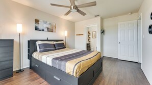 Ein Schlafzimmer mit Bett, Deckenventilator, Kommode und Tür.