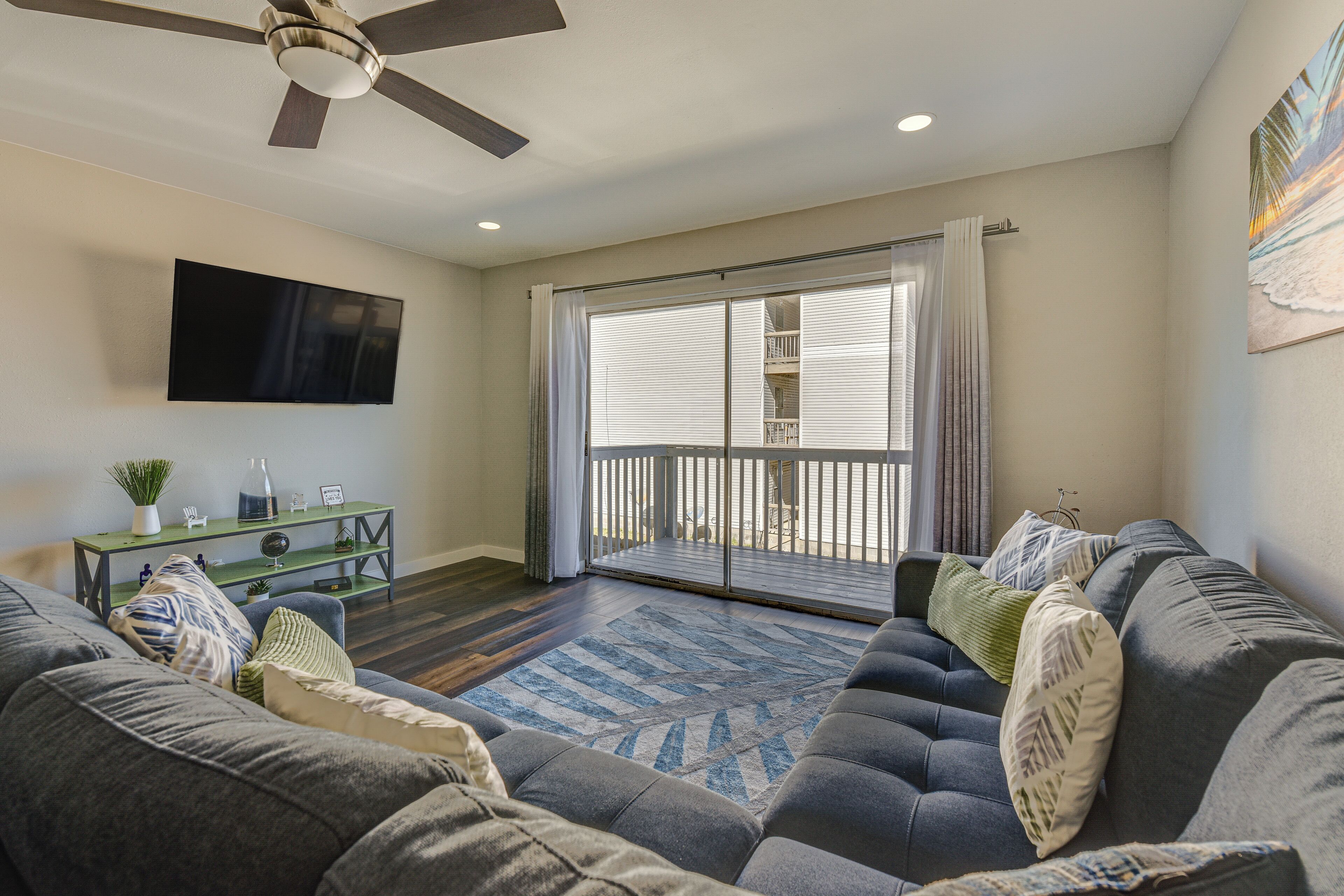 A living room with a grey sofa, a coffee table, and a flat-screen TV mounted on the wall.