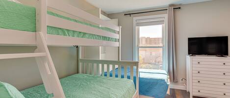 A bunk bed room with a TV and dresser.
