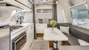 A compact RV interior with a kitchenette, dining area, and a seating space. - Airstream & Ocean View: Unique Gloucester Getaway (Gloucester)