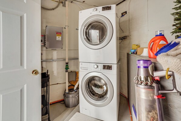 A laundry room with two stacked front-loading washing machines, a water heater, and a water filter. - Airstream & Ocean View: Unique Gloucester Getaway (Gloucester)