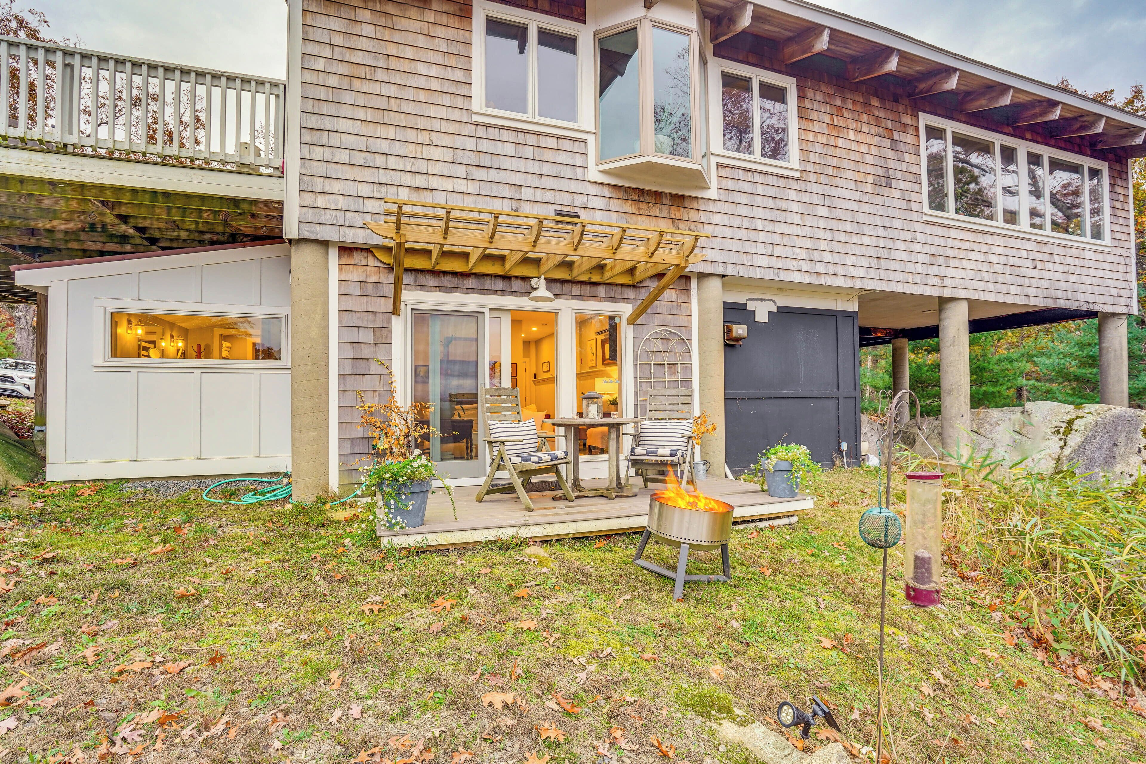 A two-story house with a covered patio, outdoor seating, and a fire pit.
