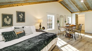 A bedroom with a bed, a dining table with chairs, and a ceiling with exposed beams.