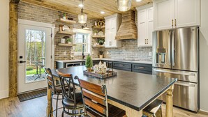 A modern kitchen with a large island, stainless steel appliances, and a rustic wooden ceiling.