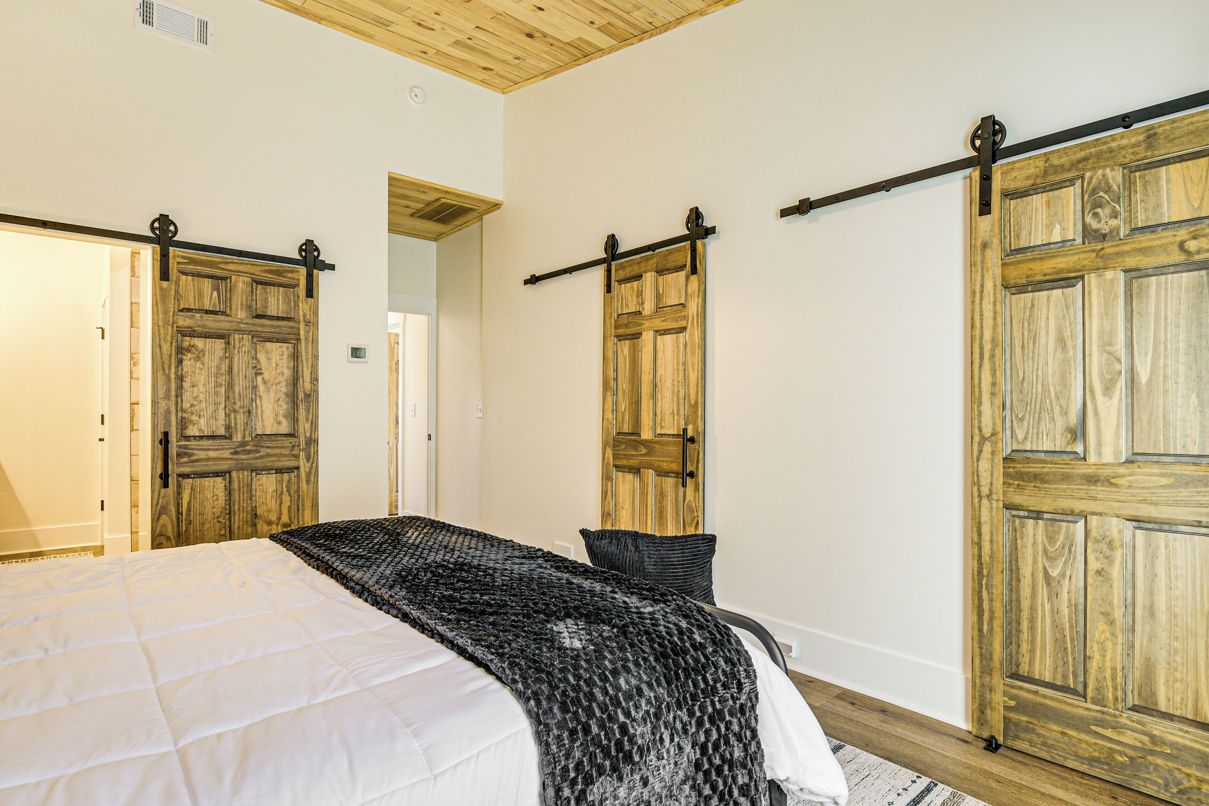 Quarto com uma cama grande, portas deslizantes de madeira e uma cadeira preta.