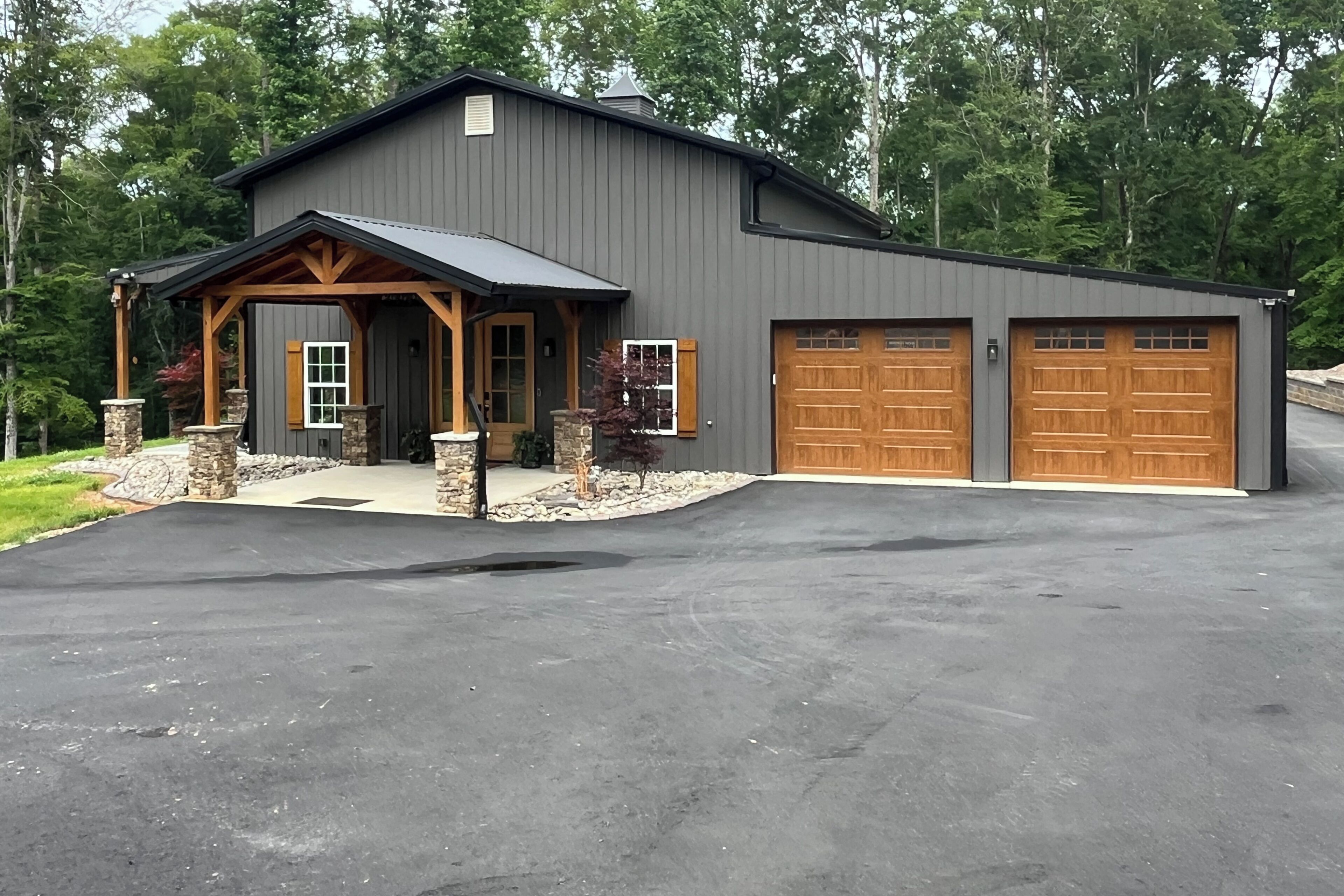 Un bâtiment à deux étages doté d’un garage, de piliers en pierre et d’un porche couvert.