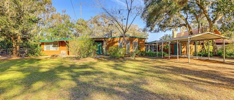A residential property with a covered patio, a fenced yard, and mature trees.