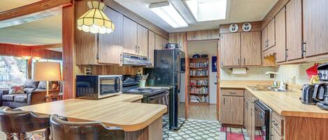 A compact kitchen with wooden cabinets, a central island, and a microwave.
