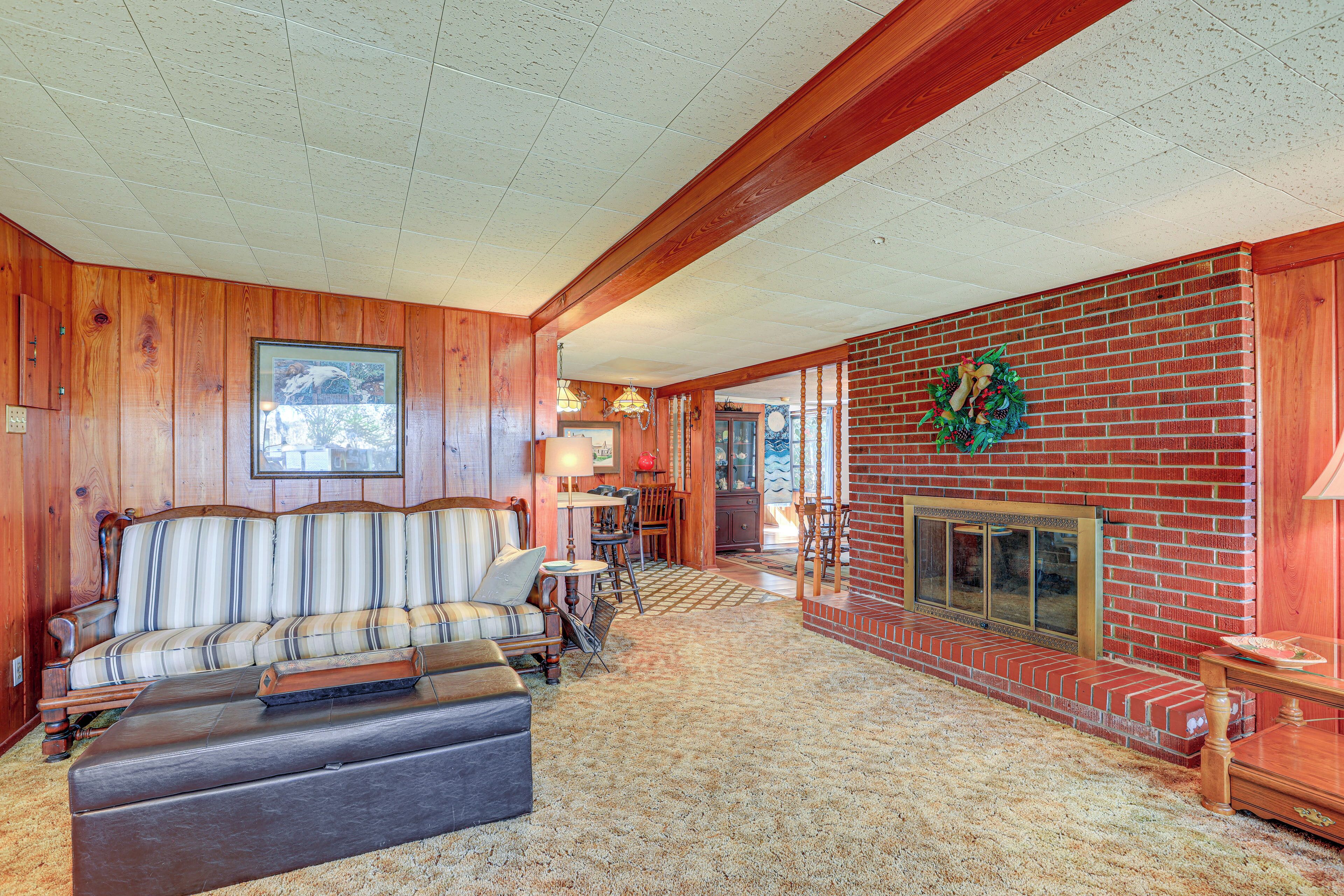 A cozy living room with a fireplace, wooden walls, and a striped sofa.