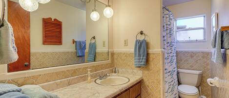 A bathroom with a double sink, a mirror, a toilet, and a shower curtain.