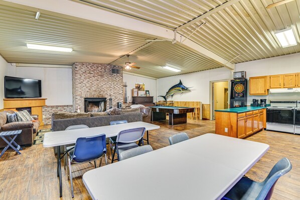 A spacious living area with a pool table, a fireplace, and a dartboard.