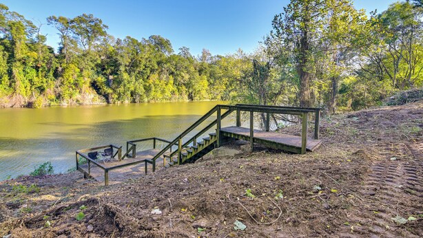 A wooden staircase leading to a bench by a lake, surrounded by trees. - Riverfront Fishing: Home in Columbus w/ Grill (Columbus)
