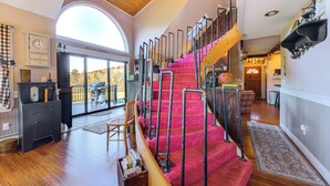 Un vaste espace de vie agrémenté d’un escalier en bois, d’une grande fenêtre et d’une cheminée.