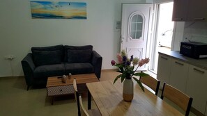 Una sala de estar con un sofá, una mesa de centro, un jarrón de flores y un cuadro en la pared.