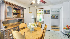 A dining area with a wooden table, chairs, a ceiling fan, and a cabinet with glass doors. - Bethlehem Home w/ Patio & Amazing Sunset Views! (Bethlehem)