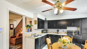 A modern kitchen with dark cabinets, a wooden dining table, and a ceiling fan. - Bethlehem Home w/ Patio & Amazing Sunset Views! (Bethlehem)