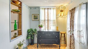 A room with a wooden dresser, a green vase, a potted plant, a wooden shelf with decorative items, and a window with curtains. - Bethlehem Home w/ Patio & Amazing Sunset Views! (Bethlehem)
