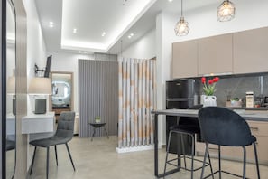 Une cuisine moderne avec un réfrigérateur noir, un coin repas avec deux chaises et une petite table avec une lampe.