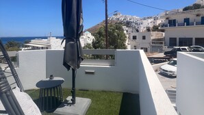 Une terrasse sur le toit, avec une table, des chaises et un parasol.