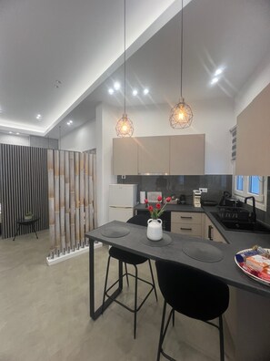 A modern kitchen with a central island, pendant lighting, and a decorative bamboo partition.