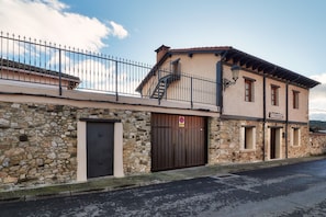A building with a stone facade, a metal fence, a staircase, and a large wooden door.