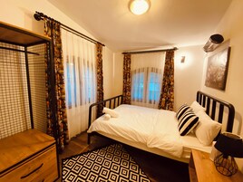 Quarto com cama, cômoda de madeira, tapete estampado e cortinas.