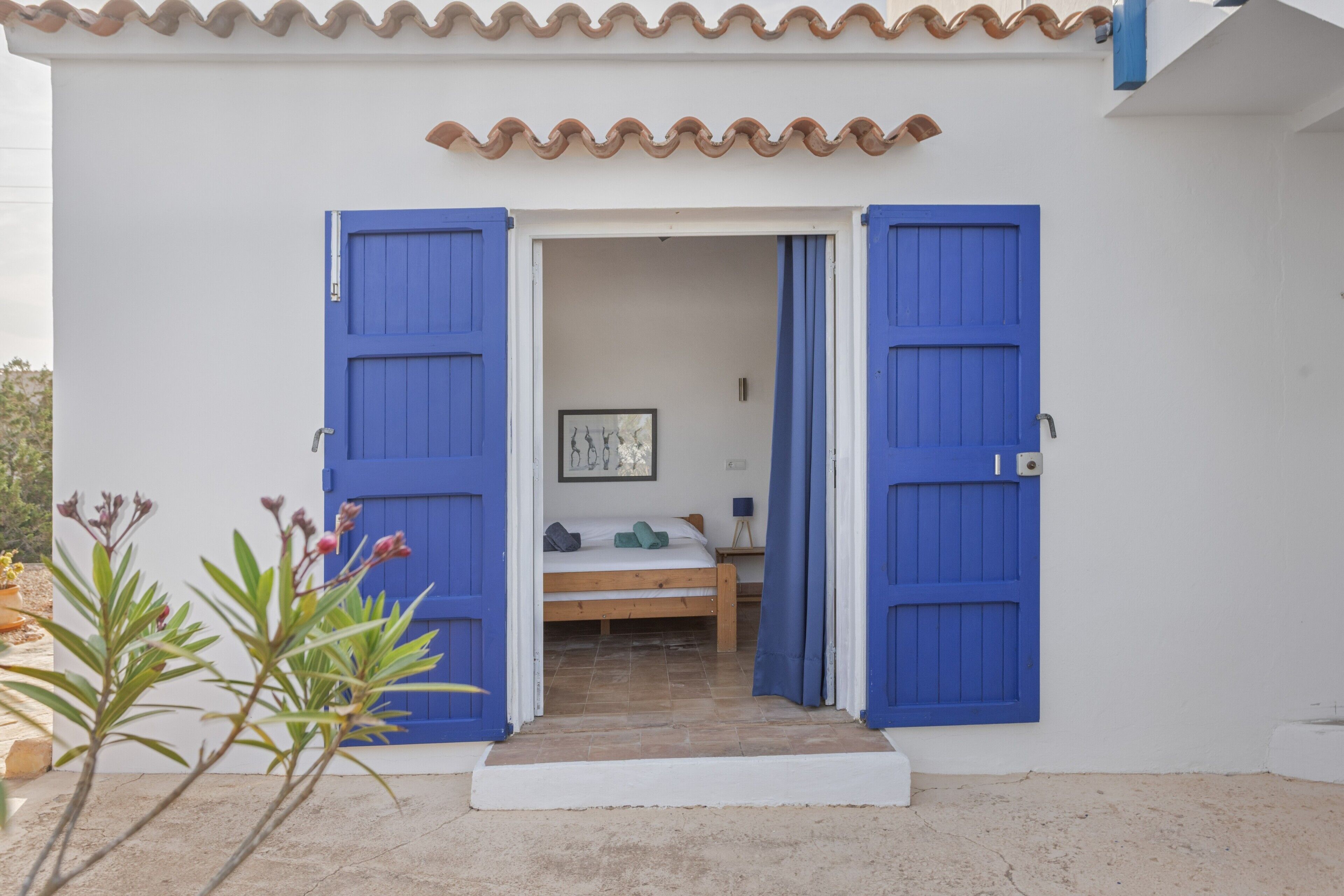 Una habitación con una cama, un cuadro en la pared y una ventana.