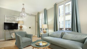 A living room with a sofa, two armchairs, a glass coffee table, a TV, and a chandelier. - Sublim and new Apartment Center of Paris / Opera (Paris)
