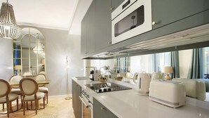 Een moderne keuken met een centraal eiland, een inbouwoven en een eethoek met een kroonluchter.