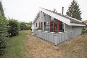 Une maison à deux étages avec un balcon, une cheminée et un jardin.