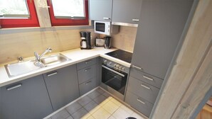 A compact kitchen with a sink, stove, microwave, and toaster. - Ferienhaus im Ferienpark Mirow (Mirow)