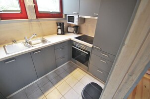 Une cuisine compacte équipée d’un évier, d’une cuisinière, d’un four à micro-ondes et d’un grille-pain.