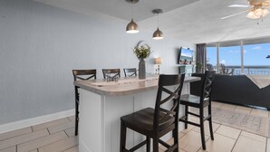 Una cocina moderna con una isla central, iluminación colgante y vistas al océano.