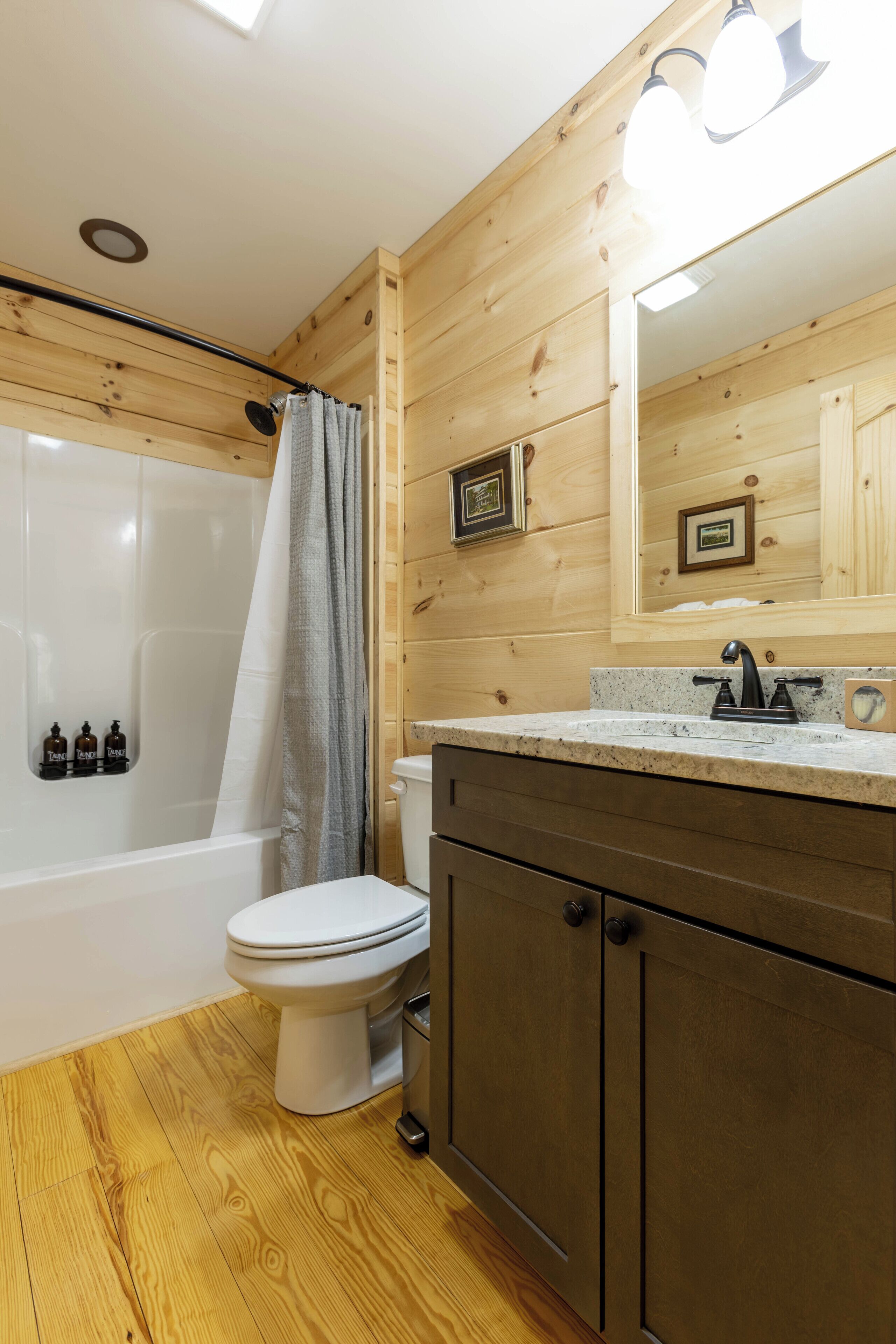 Un baño con paneles de madera, una bañera blanca, un inodoro y un tocador con espejo.