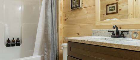 Un baño con paneles de madera, una bañera blanca, un inodoro y un tocador con espejo.