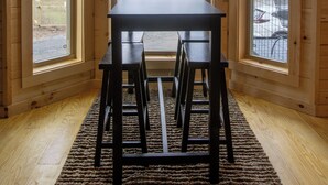 Un interno in legno con tavolo e sedie, ampie finestre e vista sull'esterno.