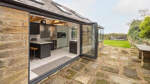 A modern kitchen with stone walls, a large glass door, and a stone pathway leading to a garden. - Host Stay Ranworth (Scarborough)