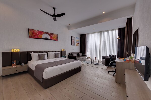 Une chambre d’hôtel moderne équipée d’un grand lit, d’un bureau, d’une chaise et d’un téléviseur.