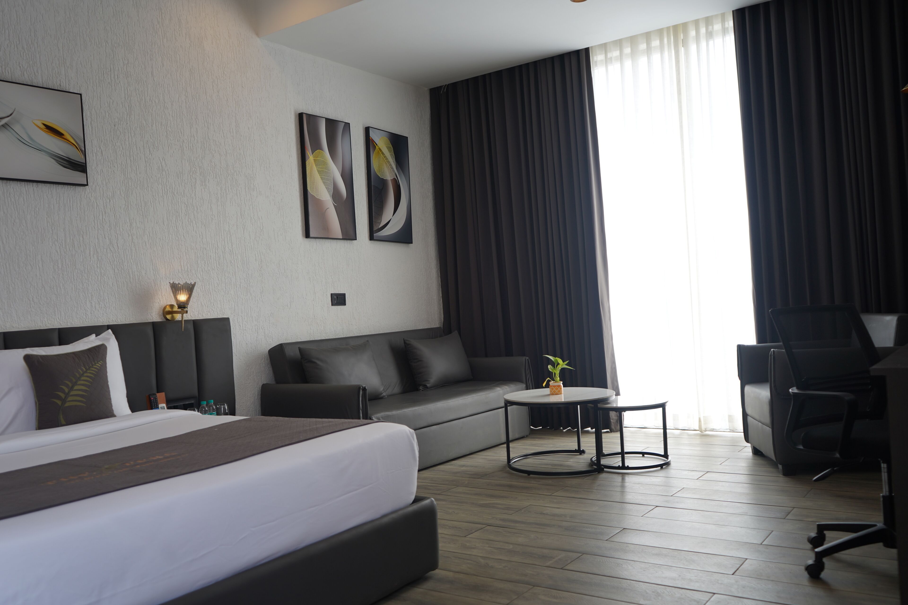 Una habitación de hotel moderna con una cama grande, un sofá, una mesita y un escritorio.
