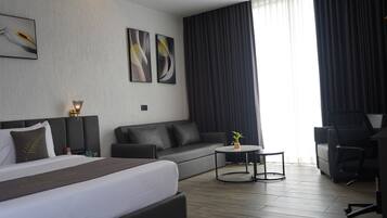 Una habitación de hotel moderna con una cama grande, un sofá, una mesita y un escritorio.