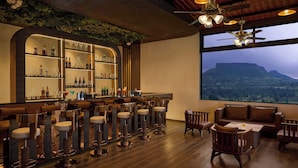 Eine Bar mit Hockern, einer Couch und einem großen Fenster mit Blick auf die Berge.