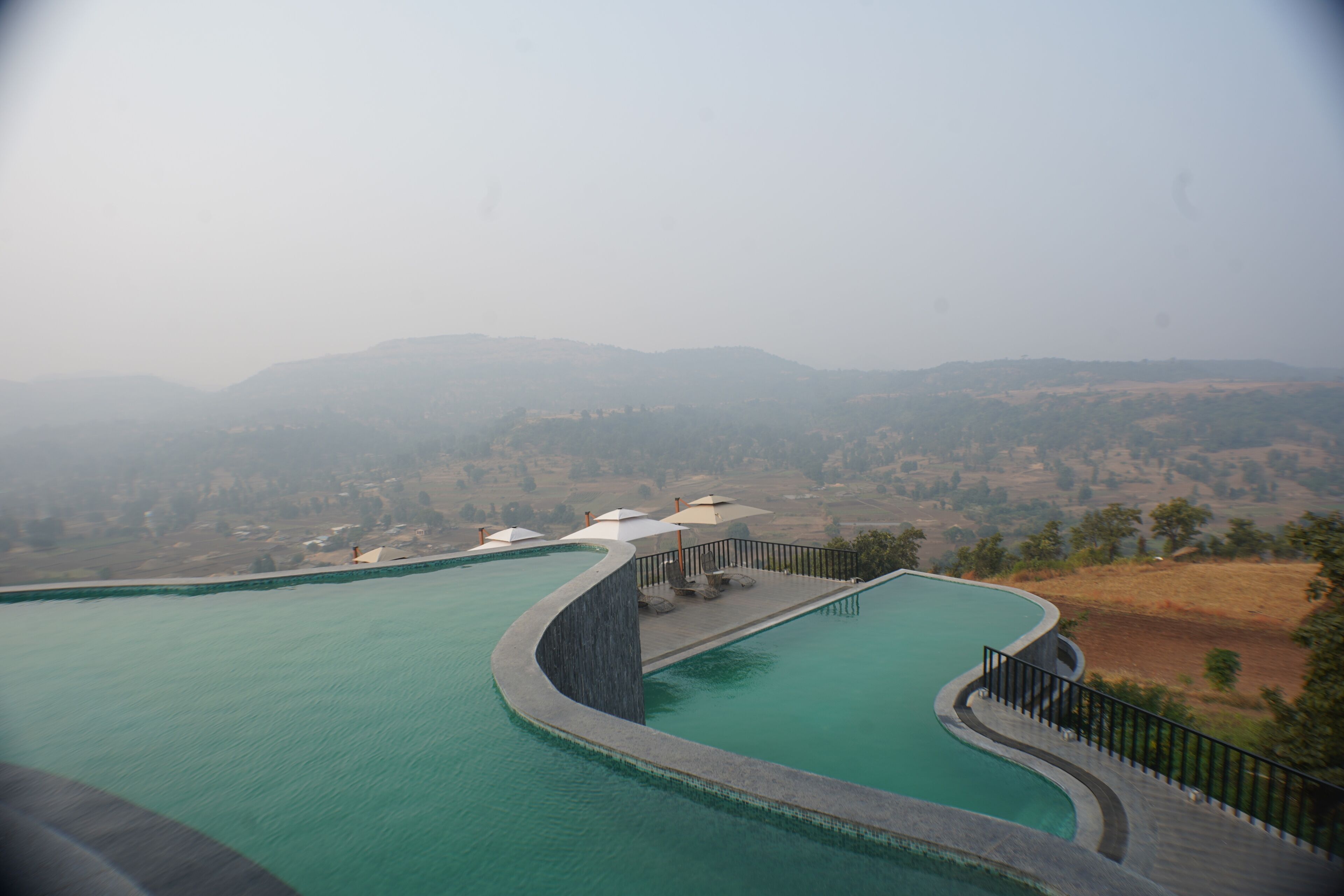 Ein Pool mit geschwungener Kante und Blick auf ferne Hügel.