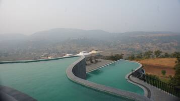Ein Pool mit geschwungener Kante und Blick auf ferne Hügel.
