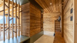 A wooden interior with a modern design, featuring a reception desk, a wall with a mountain view, and a staircase.