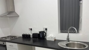 Pieni, käytännöllinen keittiönurkkaus, jossa on kaasuliesi, leivänpaahdin, vedenkeitin ja pesuallas.